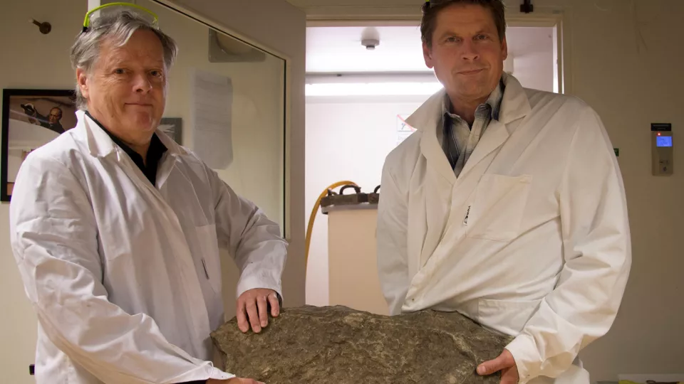 Två forskare håller i en sten. Foto