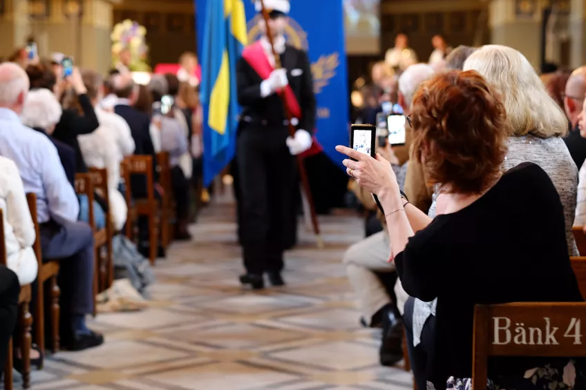 Personer i en publik fotograferar fanbärare. Foto: Helena Bergqvist.