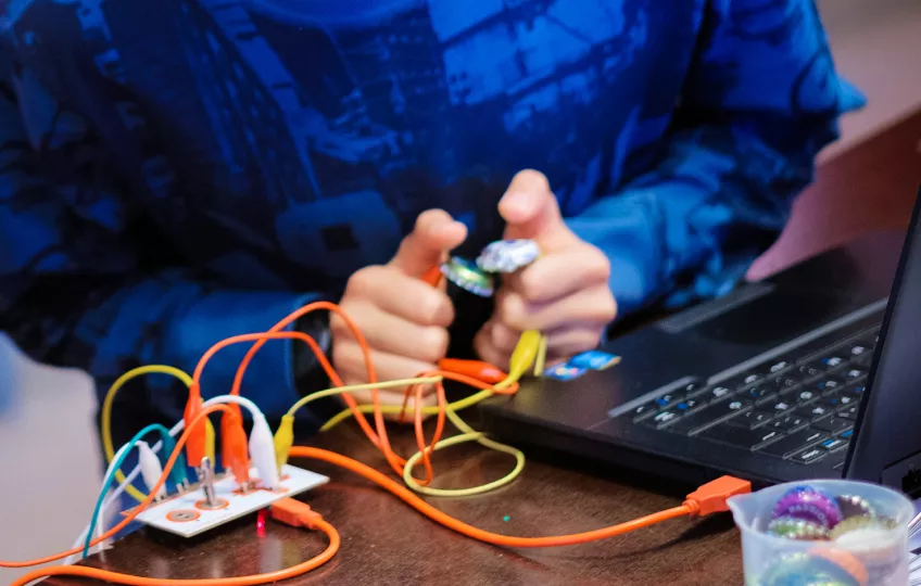 Ett barn gör ett experiment med dator och sladdar. Foto.