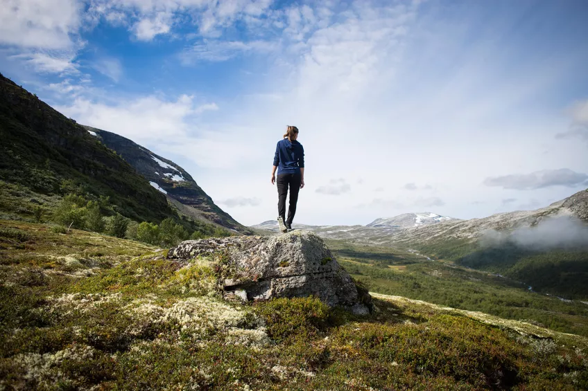 Kvinna står på en sten och tittar på utsikten. Foto.